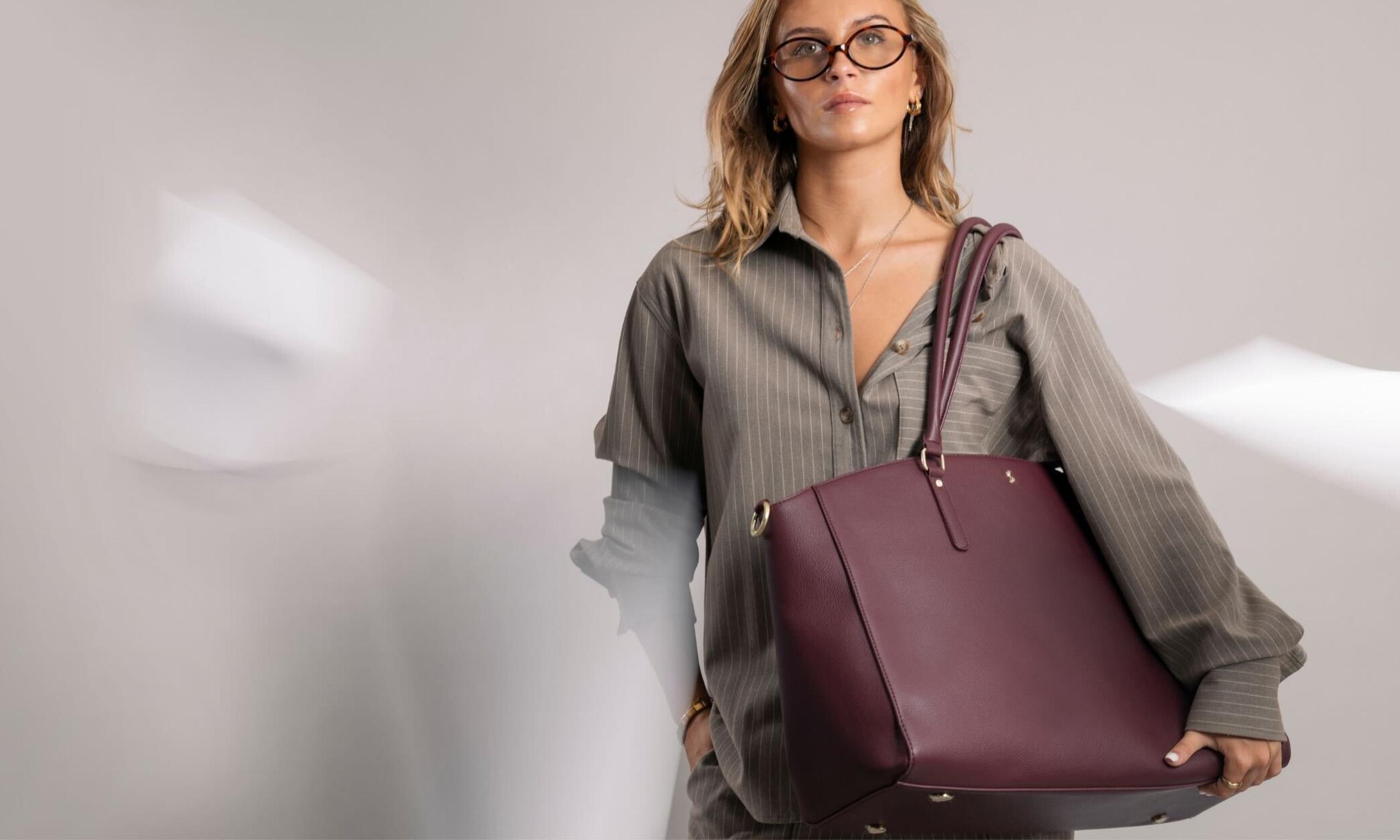 Model carrying burgundy vegan leather tote bag, perfect for back to office or university